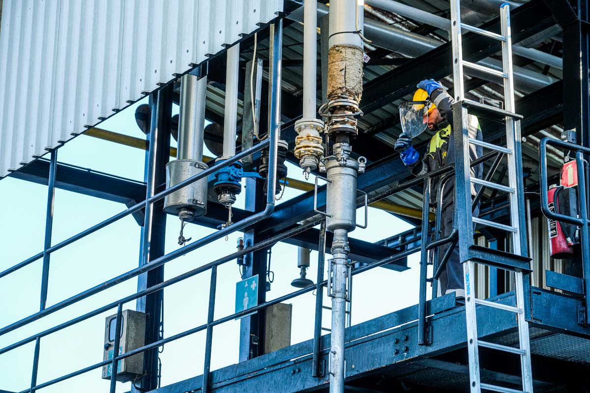 Technician performing maintenance on an industrial installation at height with safety gear